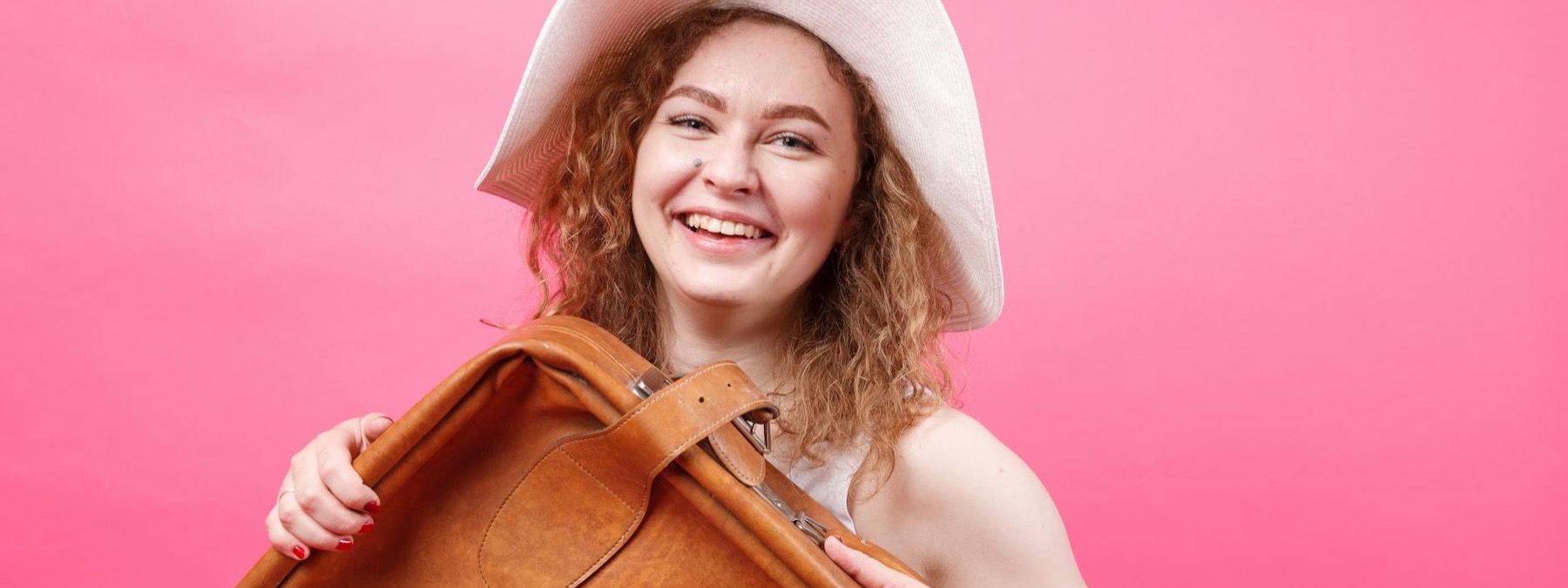 Happy young traveler smiling with a weekend bag