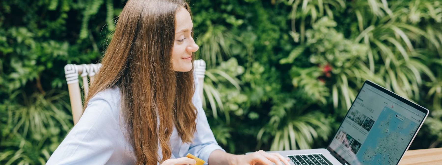 Smiling traveler using a laptop outdoors to compare assignment options